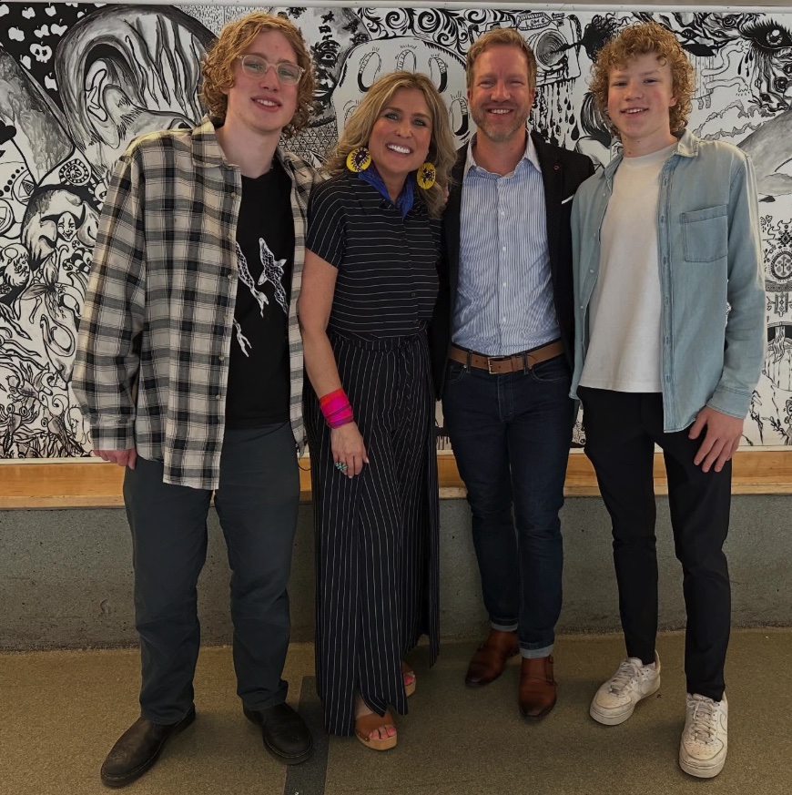 Pastor Chris and Yanci with their two sons in front of a black and white mural